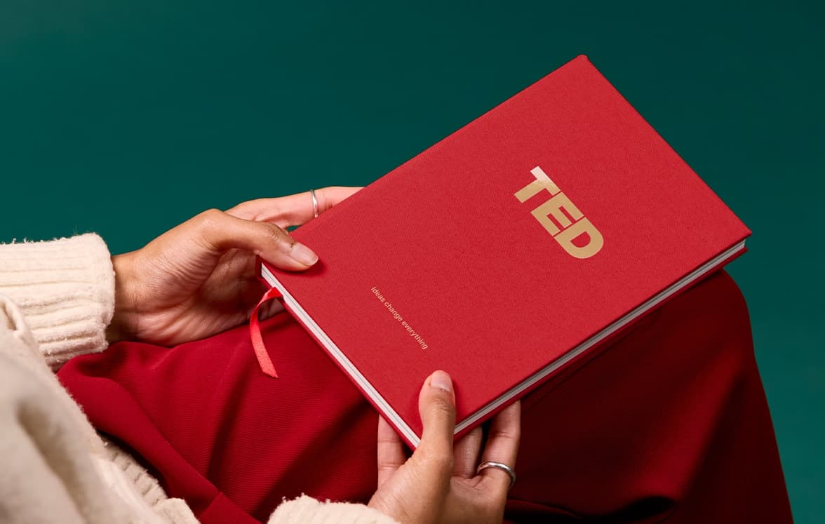 A person holding a red customized hardcover notebook with gold foil.