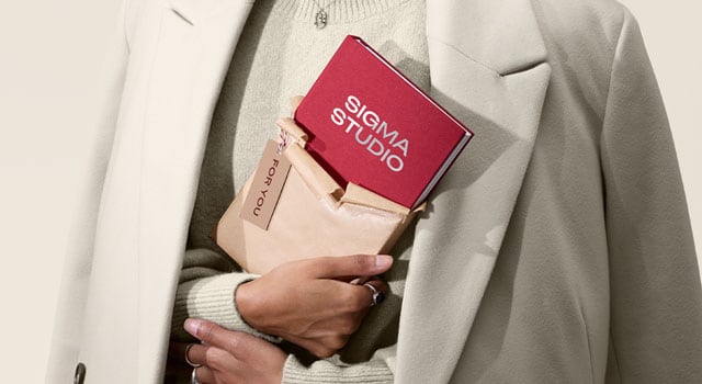 A person holding a half opened gift of a custom branded notebook with a branded gift tag