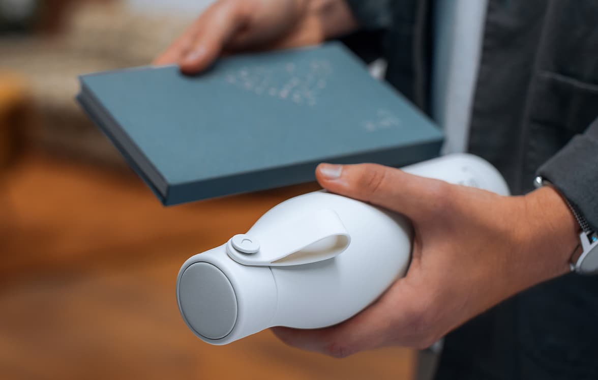 A person holding a customized notebook in one hand and a water bottle in the other.